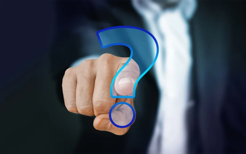 A hand reaching toward a large illuminated question mark.